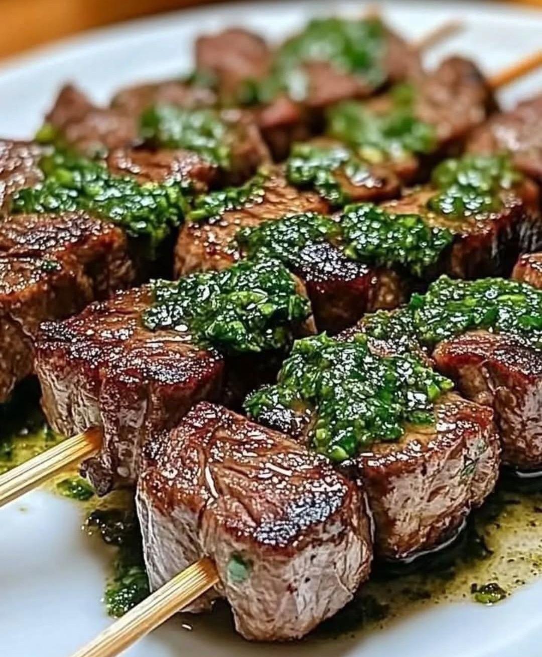 Grilled beef skewers with fresh chimichurri sauce and herb garnish